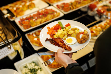 Guest picks up different food at the breakfast buffet at the hotelの写真素材