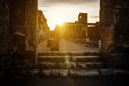 An ancient, partially ruined temple stands bathed in the golden hue of a setting sun