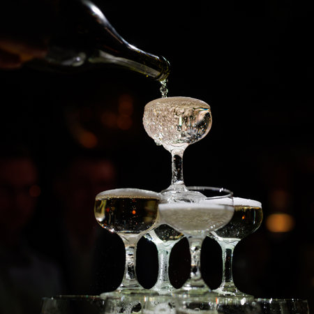 Waiter pouring champagne on a pyramid tower on a dark backgroundの写真素材
