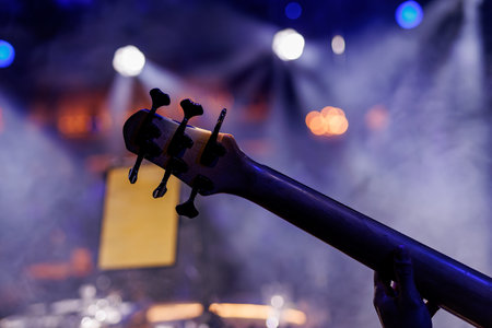 Tuning pegs of a Bass guitar, set against a bokeh effect of concert lightsの写真素材