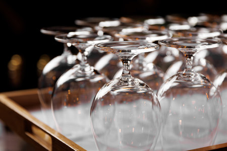 Empty crystal-clear wine glasses inverted on a wooden tray