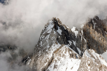 A majestic mountain peak pierces through a blanket of clouds.の写真素材