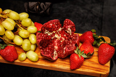 A vibrant assortment of fresh fruits, including grapes, strawberries, and an open pomegranateの写真素材