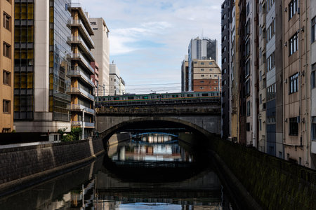 The train is going through the city. Canal with charming buildings and an elevated train in a vibrant urban settingの写真素材