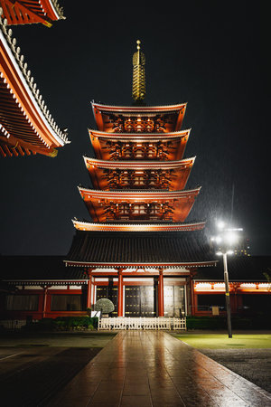 Traditional Japanese pagoda beautifully surrounded by traditional architecture at rainy nightの写真素材