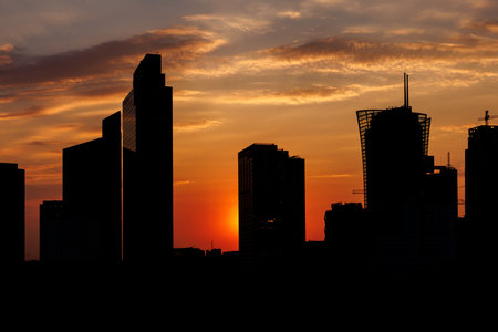 The towering silhouette of skyscrapers stands out against a vibrant sunsetの写真素材