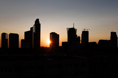 A stunning silhouette of a city skyline remarkably displayed against a beautiful sunsetの写真素材