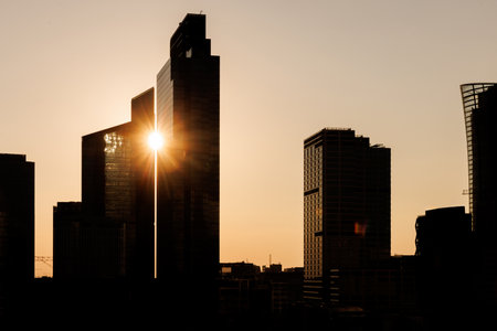 A sunset casts a warm glow over skyscrapers, creating a breathtaking silhouette against the evening sky.の写真素材