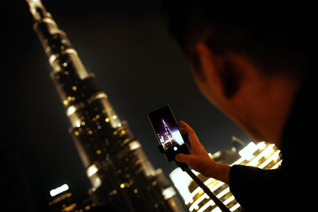 Tourist in Dubai takes pictures of landmarks with his smartphoneの写真素材