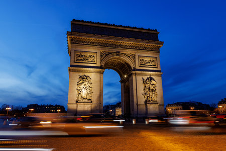 The Arc de Triomphe in Paris is lit up at nightの写真素材