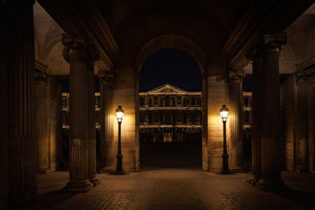 A dark, empty building with a large archway. The archway is lit up by two lampsの写真素材