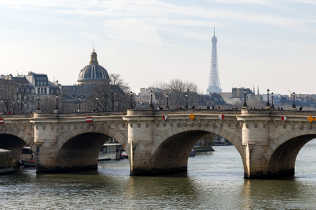 A beautiful bridge spans a river, with a stunning view of the Eiffel Tower in the distanceの写真素材