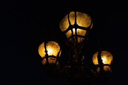 A lamp with three lights is lit up in the dark. The light is warm and invitingの写真素材