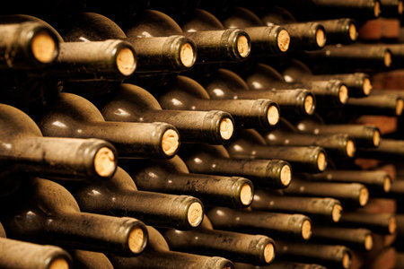Dusty bottles of wine lie on top of each other in the rustic cellarの写真素材