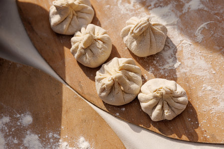 A wooden table with a white cloth on it. There are five dumplings on the tableの写真素材