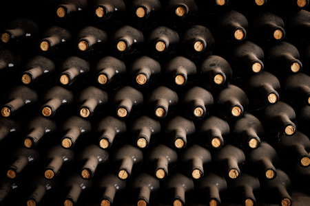 Old dusty bottles of wine are left on top of each other in the cellarの写真素材