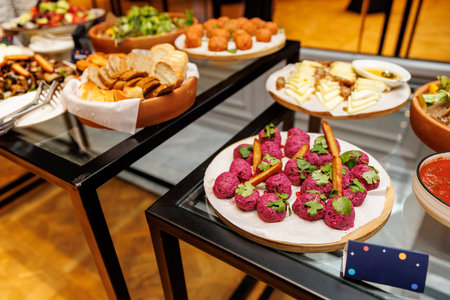 A table with a variety of food items including a plate of meatballs and a bowl of fruitの写真素材