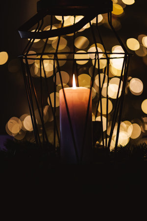 Glowing candle inside a metal lantern creates a warm and cozy ambiance with a soft bokeh effect in...