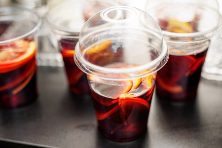 Cold sangria served in transparent takeaway cups with fruit slices. Refreshing summer drink.の写真素材