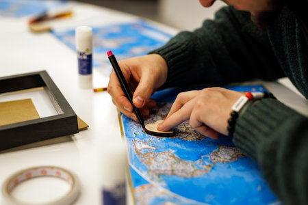 Person drawing on a map with wooden heart shapeの写真素材