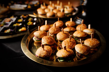 Close-up of multiple mini burgers on a gold tray. Suitable for catering, events, or food menu...