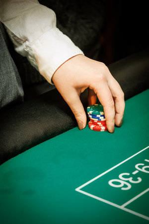 Gambler placing chips on a green felt table. Great for betting, risk, or entertainment-related content.の写真素材