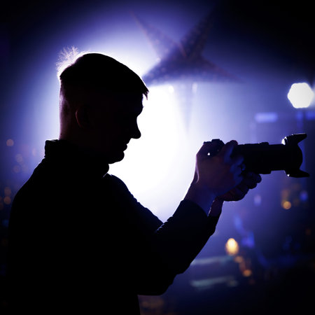 Silhouette of photographer with camera at event with dramatic lighting