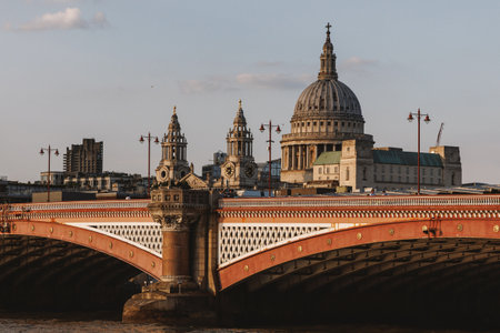 View of St Paul's Cathedral dome behind Blackfriars Bridge in London illuminated by warm evening sunlightの写真素材