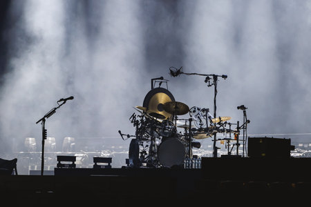 A complex drum set stands ready on a smoke-filled stage lit by spotlights, waiting for the show to start.の写真素材