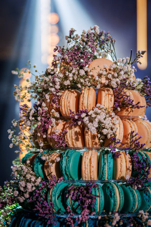 Detailed view of turquoise and cream macarons decorated with delicate flowers on a tiered dessert...