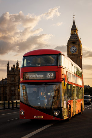A classic red bus crosses Westminster Bridge at golden hour with Elizabeth Tower in the background....