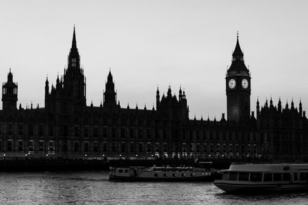 Boats passing on the River Thames in front of the illuminated Palace of Westminster and Big Ben at...