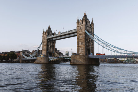 Wide view of Tower Bridge crossing the Thames at calm water level. Evening light and soft sky frame the iconic London landmark.の写真素材
