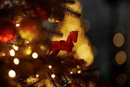 A backlit red toy horse decoration stands out against a background of bright yellow holiday bokeh.の写真素材