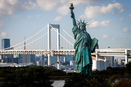 A bronze copy of the iconic American monument stands in the foreground of a coastal park. The massive white suspension bridge spans the bay behind it.の写真素材