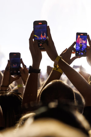 A vertical POV shot from a fan's perspective recording a live music performance on a smartphone with...
