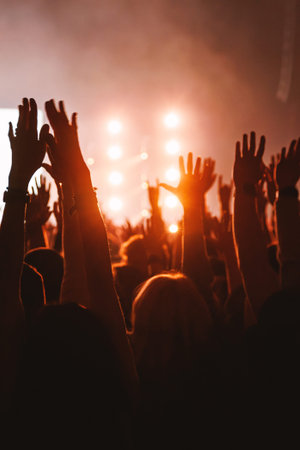 Silhouettes of fans reach their arms toward the stage during a thrilling musical performance....