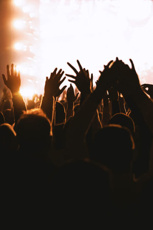 Point of view shot deeply immersed in a concert audience. Silhouettes of fans raise their hands...