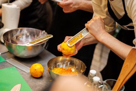 A close-up view of a cook using a handheld grater to collect citrus zest for a recipe.