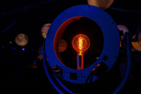 A glowing orange filament light bulb centered within a circular metallic frame.