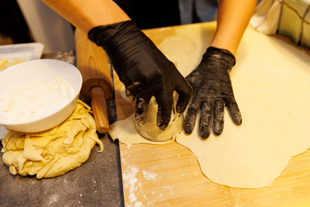 A close up view of the process of making handmade dumplings. The scene includes a rolling pin,...