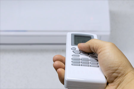 Hand holding air conditioner remote control. Selective focus.