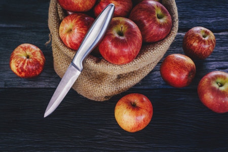 Apple in sack and knife on wood backgroundの写真素材
