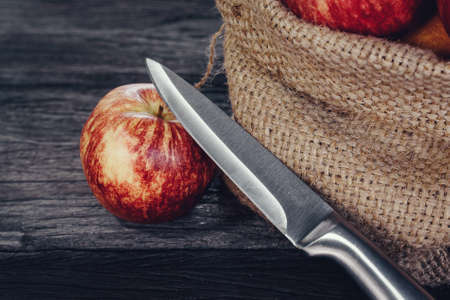 Apple in sack and knife on wood backgroundの写真素材