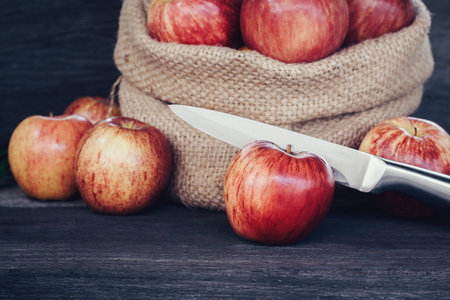 Apple in sack and knife on wood backgroundの写真素材