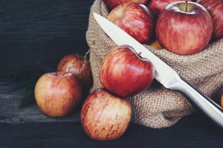 Apple in sack and knife on wood backgroundの写真素材