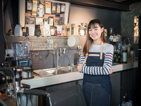 Asian woman barista smiling standing at the coffee shop counter, female successful in small business owner.の写真素材