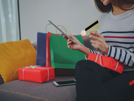 Asian young woman Smiling in santa hat with gift box, tablet pc computer and credit card, shopping online concept.の写真素材