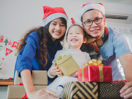 Asian young family on Christmas exchanging presents and enjoying their time together. Focus on the little girl.の写真素材