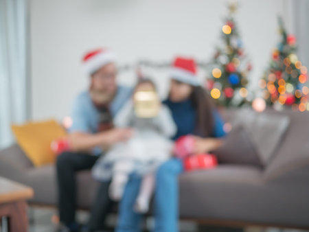 Blurred background asian young family on Christmas exchanging presents and enjoying their time together. Focus on the little girl.の写真素材